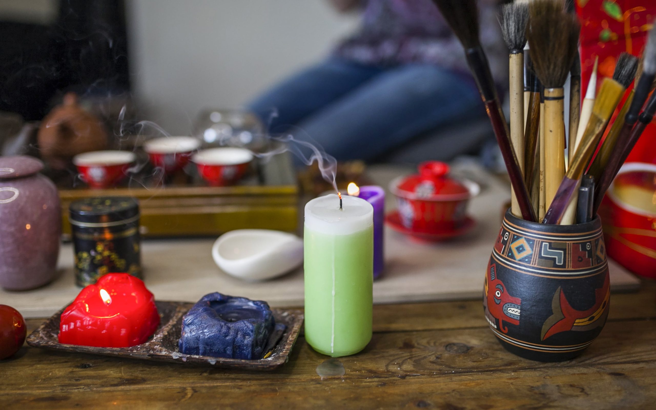 extinguished-candle-with-smoke-front-tea-set-wooden-table-min